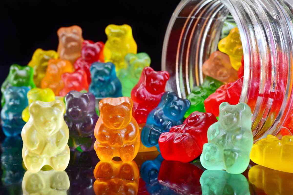 Assorted rainbow gummy bears spill from a plastic bottle. An increasing number of people use CBD gummies for anxiety and depression.